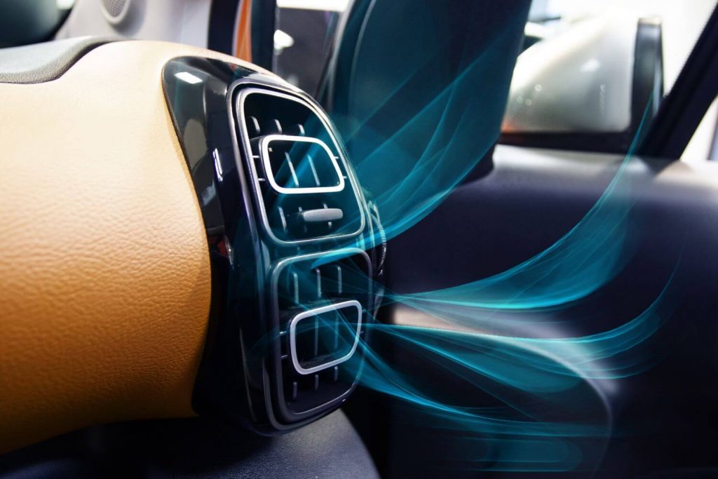 Connected controls for heating, ventilation and air conditioning in the interior of a car with ventilation grille and blue air flow.